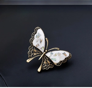 Detailed close-up of shell butterfly brooch with gold metal and mother-of-pearl inlay