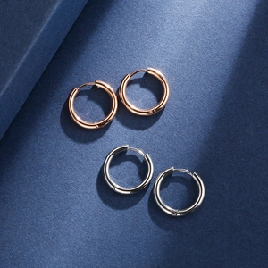 Polished silver and rose gold stainless steel hoop earrings on dark blue background