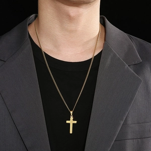 Pendentif croix en or poli porté par un mannequin en costume pour un style élégant