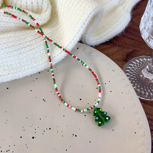 Close-up of a festive Christmas beaded necklace with a green glass tree pendant detail