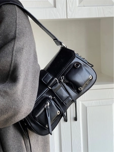Close-up of black multi-pocket shoulder bag with silver hardware and synthetic leather detail