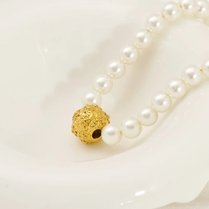 Collier de perles blanches élégant avec pendentif fleuri doré sur plateau ondulé
