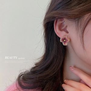 Elegant flower stud earrings with purple crystals on a female model in soft light