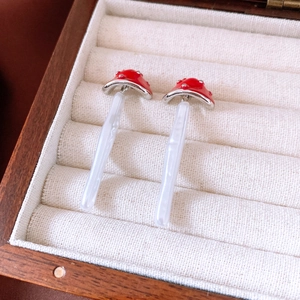 Detail of red mushroom earrings with silver dots in a premium wooden jewelry box