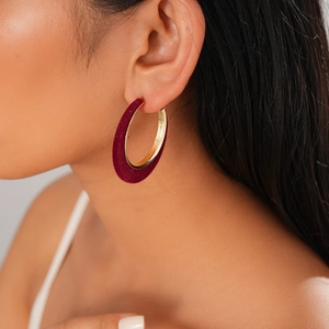 Close-up of red velvet and gold metal hoop earring worn on woman's ear for autumn style