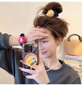 Détail de chouchous rouges et jaunes mignons avec breloque lettre 'm' au poignet et cheveux