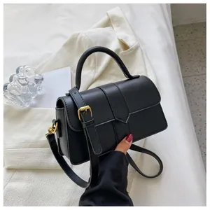 Détail du sac bandoulière noir avec boucle dorée et poignée supérieure élégante