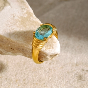 Detail of a vintage 18k gold plated ring with large oval blue stone on natural stone surface