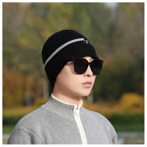 Detail einer schwarzen Strickmütze mit grauem Streifen und FU-Stickerei, dazu Sonnenbrille