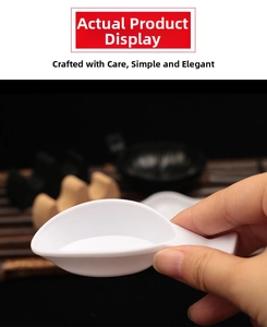 White leaf-shaped plastic brush rest for calligraphy shown held by hand for scale