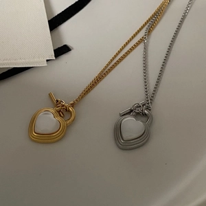 Detailed close-up of heart cat-eye pendants with OT buckle on titanium steel necklaces