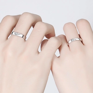 Polished silver couple rings featuring interlocking half-heart design and small zircon stones