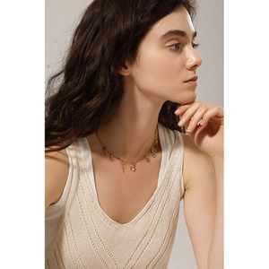 Detail of 18K gold stainless steel necklace with DIY charms worn by a model in soft lighting