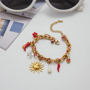 Détail du bracelet en acier inoxydable doré 18K avec breloques rouges et pendentif soleil