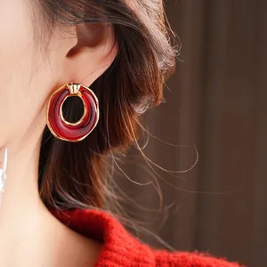 Retro resin round earrings with gold trim on model wearing red sweater