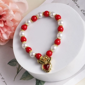 Makro-Detail von roten Perlen und Perlenarmband mit goldenem Hasen-Herz-Anhänger