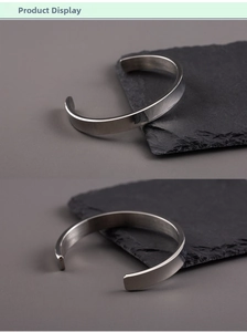Detailed close-up of 8mm brushed silver stainless steel cuff bracelet on a stone stand