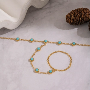 18K gold-plated stainless steel hand chain with turquoise beads on white marble surface