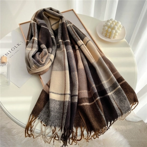 Classic brown plaid scarf with fringe on a white table with minimalist winter decor