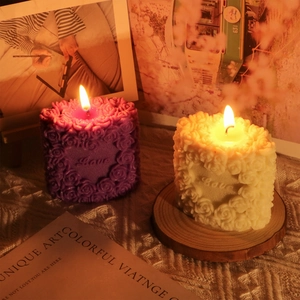 Detailed relief of rose patterns and Love text on lit heart-shaped pillar candle