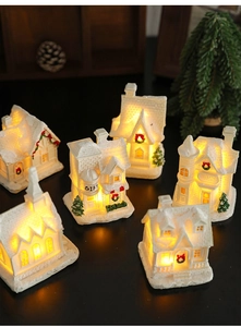 Close-up of glowing miniature resin snow house ornaments with warm LED lights for Christmas