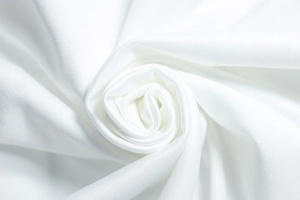 Macro shot of white knitted fabric texture showing soft pleats and fine weave details
