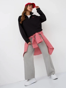 Detail of black quarter-zip sweatshirt with red bunny embroidery and relaxed street style