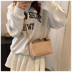 Detail of the light brown crossbody bag featuring rich rabbit embossed pattern and metal buckle