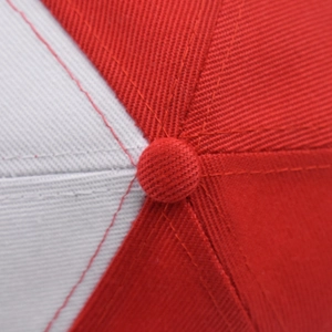 Macro shot of the red and white twill cotton fabric seams and top button on a baseball cap