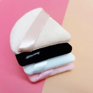 Set of four colorful velvet powder puffs in beige, black, blue, and pink for makeup