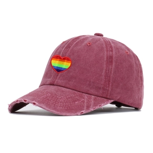 Close-up of distressed wine red baseball cap with rainbow heart embroidery detail