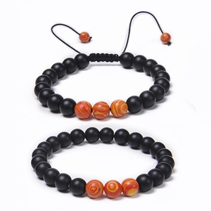 Détail de perles noires mates et de bracelets en pierre rouge avec cordon réglable