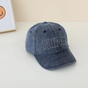 Dettaglio del ricamo KING su cappellino in denim lavato con trama di tessuto chiara