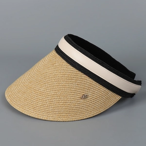 Detail view of woven straw sun visor with wide brim, leather trim and metal emblem