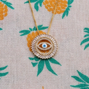 Vintage gold Turkish evil eye necklace with blue zircon stones on pineapple fabric