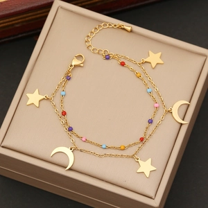 Golden double-layer bracelet with stars, moons and multicolored beads on a jewelry box