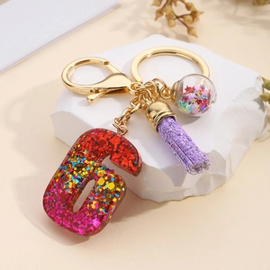 Detail of glitter resin number 6 keychain with purple tassel and star glass ball charm