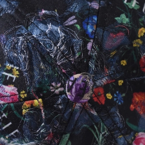 Macro shot of navy blue baseball cap featuring distressed fabric and floral pattern details