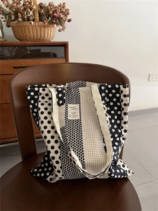 Dettaglio della borsa tote in tela a pois con motivi geometrici su una sedia in legno