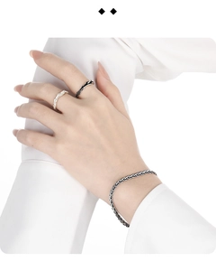 Detail showing vintage snake bone chain bracelet and silver rings on a wrist with white sleeve