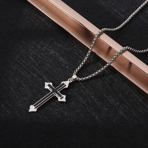 Detailed view of silver and black cross pendant on a textured dark background