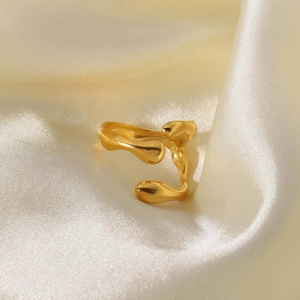 Macro view of a gold geometric textured ring placed on soft beige silk fabric