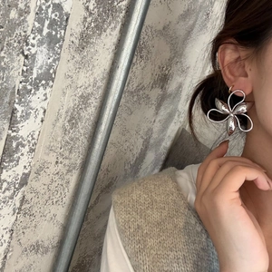Close-up of a model wearing large silver 5-petal flower earrings with high-end metal texture