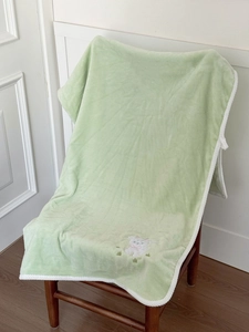 Detail of soft green lamb towel with white rope edge and cute animal embroidery