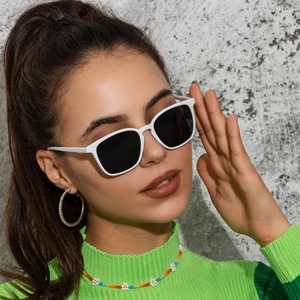 Retro square white frame sunglasses with black lenses worn by model in green sweater