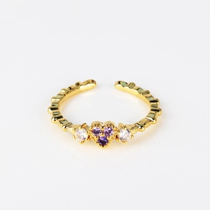 Macro detail of adjustable 18K gold ring featuring purple heart-shaped zircons and wavy band