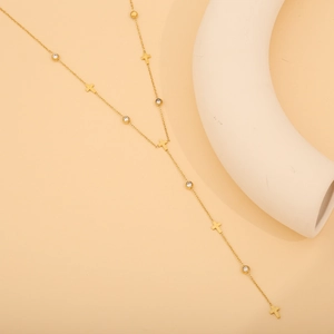 Gros plan du collier en Y doré avec des breloques en croix et zircons blancs brillants