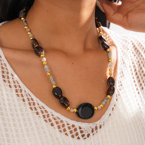 Close-up of bohemian beaded sweater chain with oval pendant on a white mesh top
