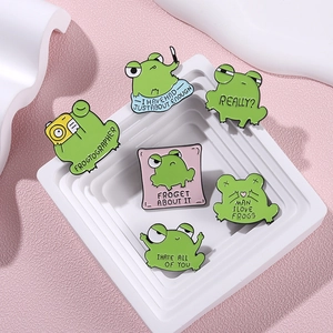 Set of 6 green cartoon enamel frog badges with funny English puns on a pink display