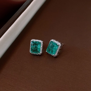 Detailed view of silver stud earrings featuring emerald cut green zircon and crystal halo